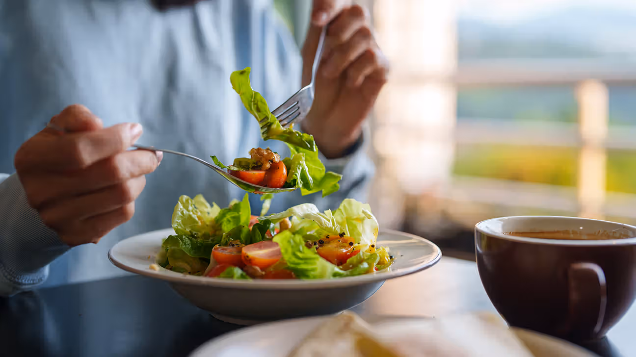 woman-eating-fresh-salad-tomatoes-lettuce-nuts-cup-of-coffee-1296x728-header